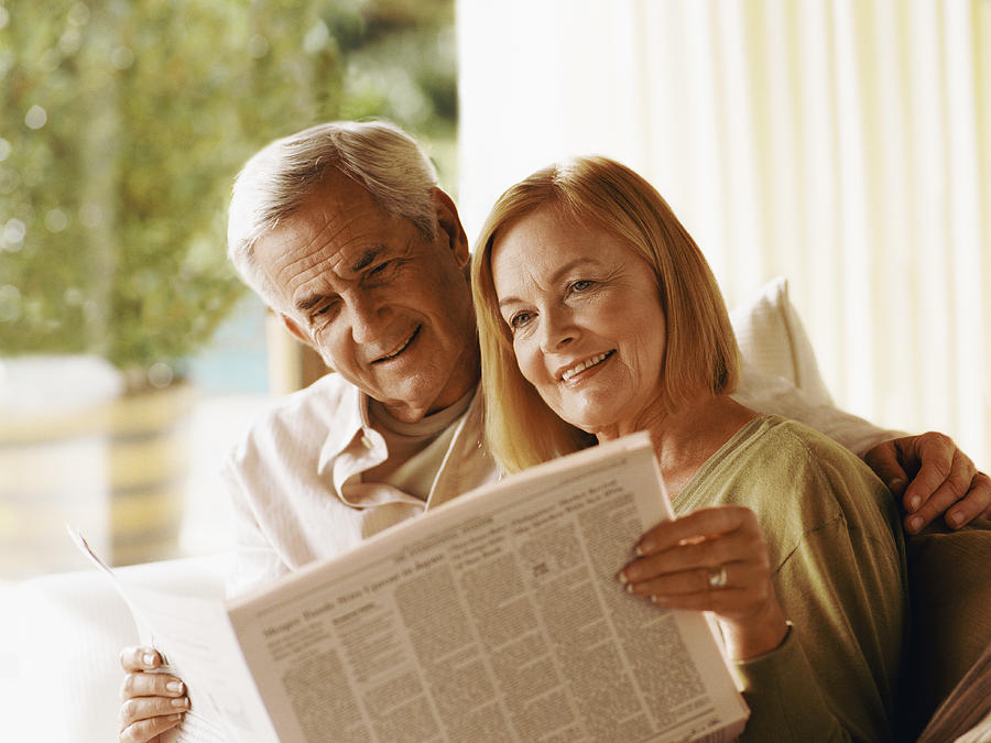 Senior Couple Sitting Indoors Together Reading a Newspaper Photograph by Flying Colours Ltd