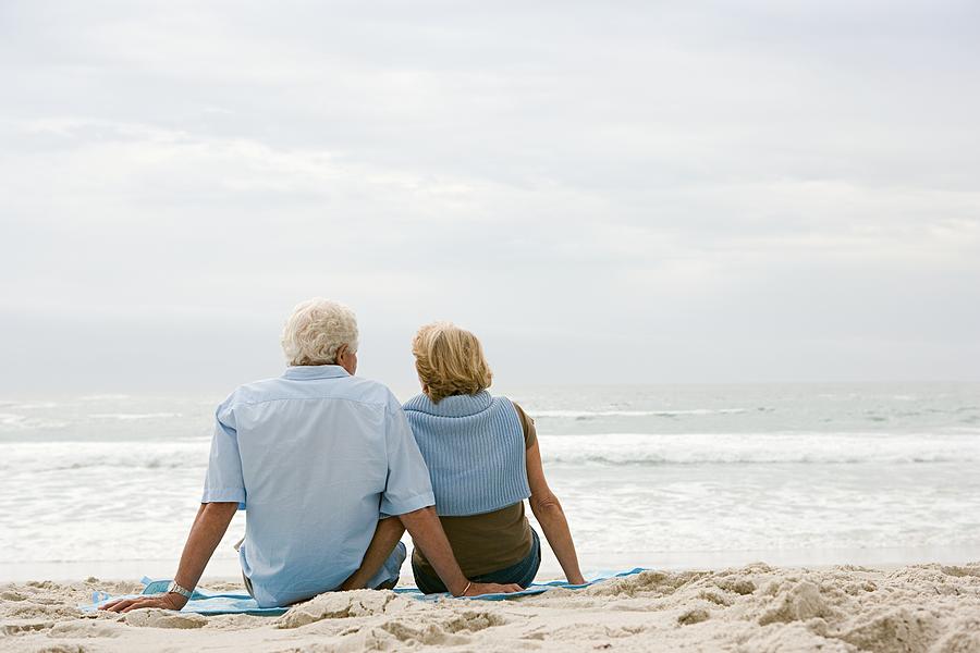 Senior couple sitting on a beach Photograph by Image Source