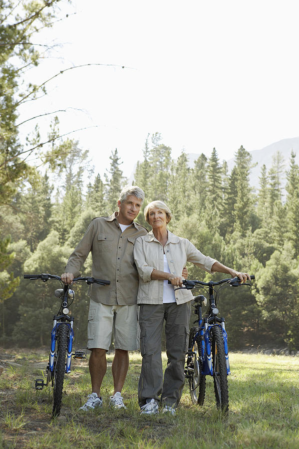 Senior Couple Standing Side by Side With Their Bikes With Woodland in the Background Photograph by Dylan Ellis
