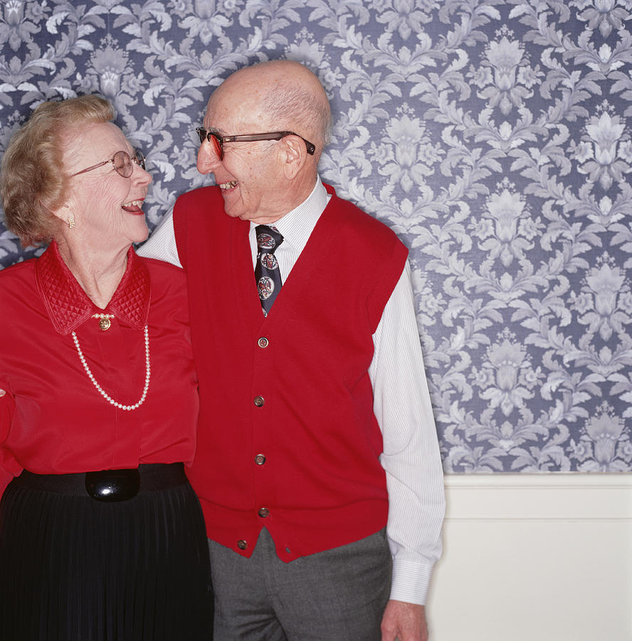 Senior couple standing together laughing, indoors, portrait Photograph by Ryan McVay