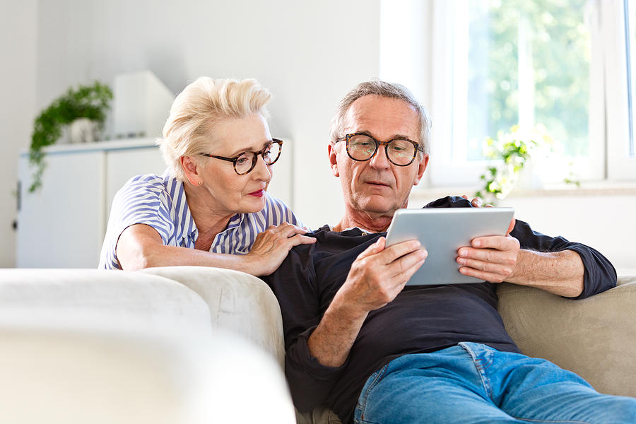Senior couple watching digital tablet together at home Photograph by Izusek