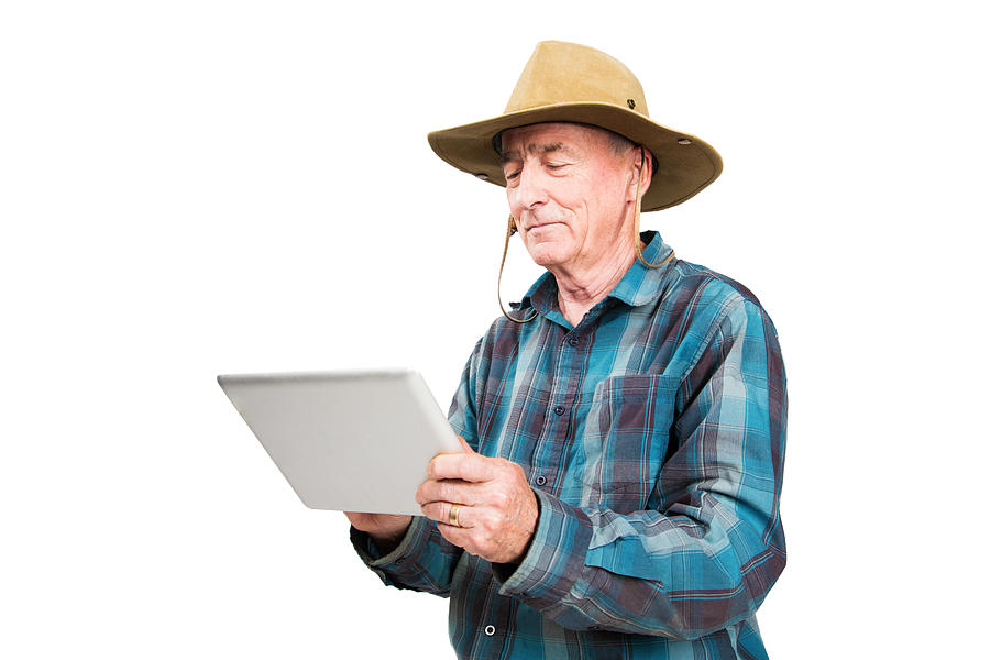 Senior farmer using digital tablet isolated Photograph by NicolasMcComber