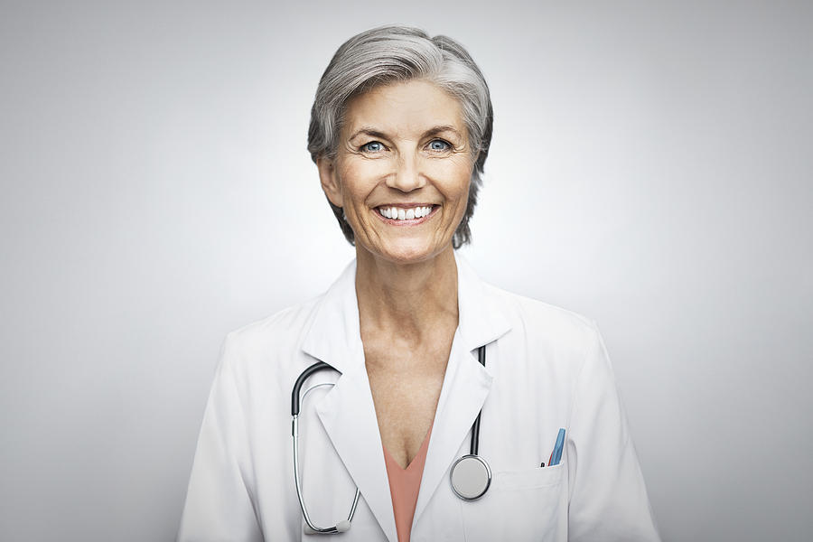Senior female doctor smiling on white background Photograph by Morsa Images