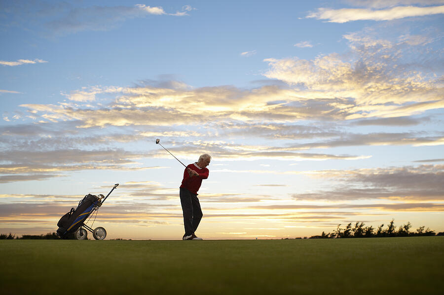Senior golfer about to tee off at sunset. Photograph by Dougal Waters