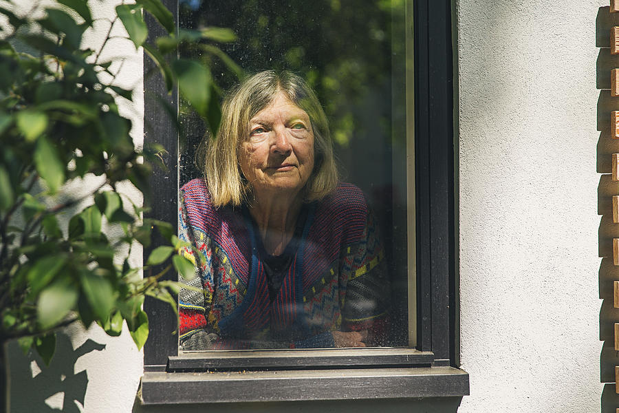 Senior lady looking through window Photograph by Justin Paget