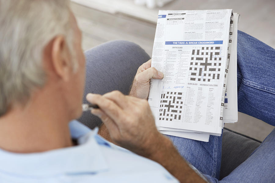 Senior Man Contemplating a Newspaper Crossword Photograph by Digital Vision.