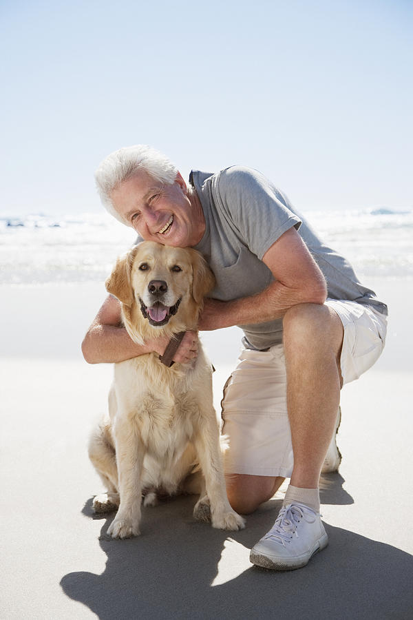Senior man hugging dog on beach Photograph by Robert Daly