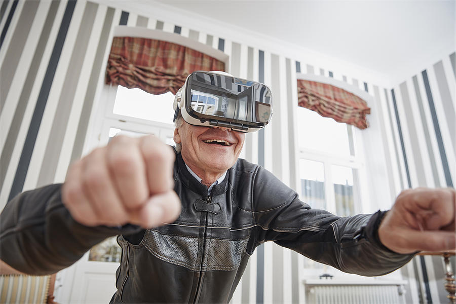 Senior man in motorcycle suit wearing VR glasses Photograph by Westend61