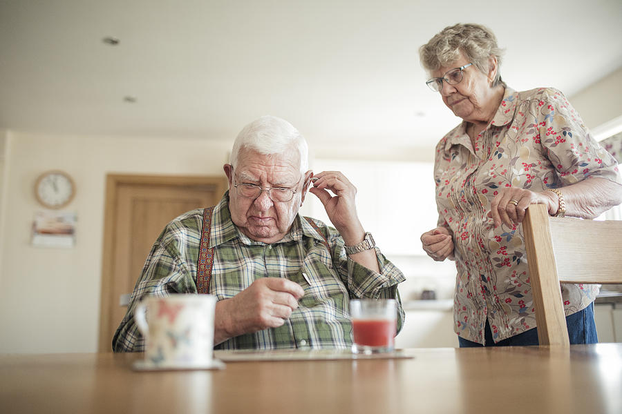 Senior Man Inserting His Hearing Aid Photograph by SolStock
