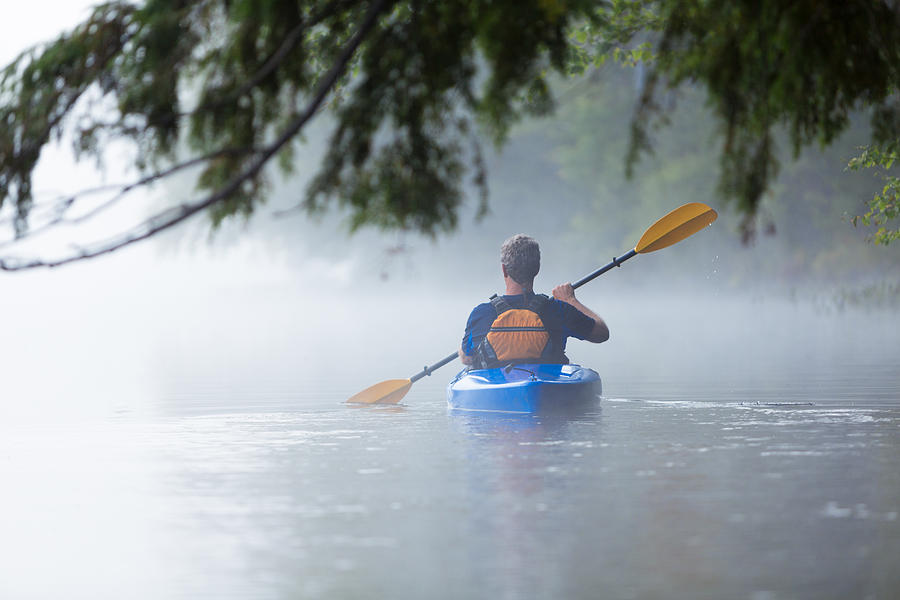 Senior man kayaking in morning mist Photograph by Cglade