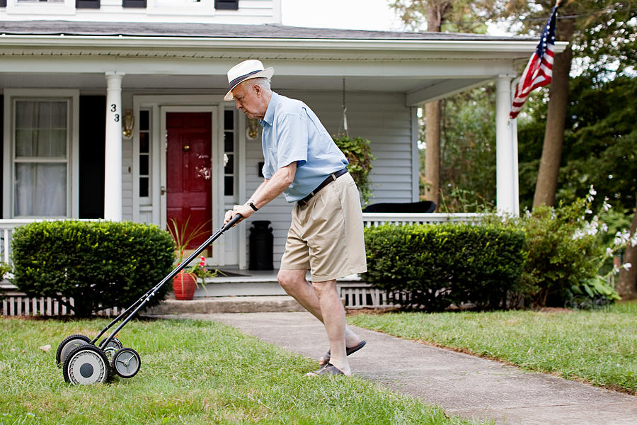 Senior man mowing his front lawn Photograph by Image Source