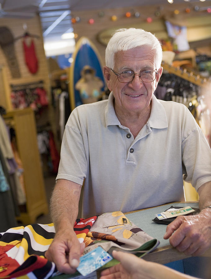 Senior man purchasing items with credit card in store Photograph by Marc Romanelli