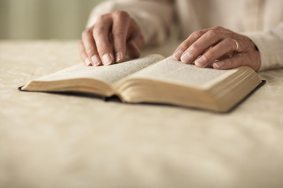 Senior man reading Bible, close-up of hands Photograph by Thomas Northcut