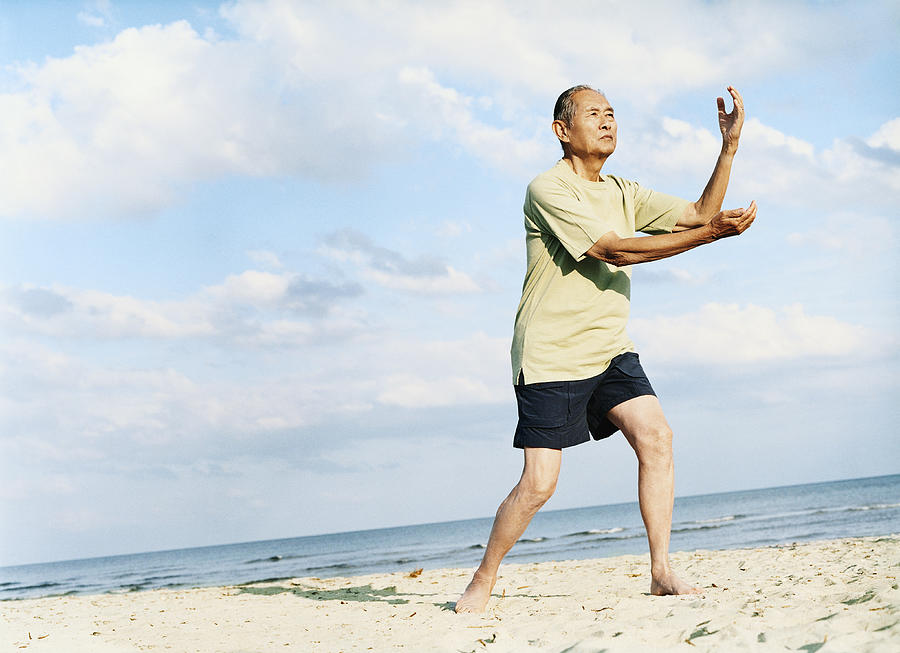 Senior Man Stands on the Beach Doing Tai Chi Photograph by Digital Vision.