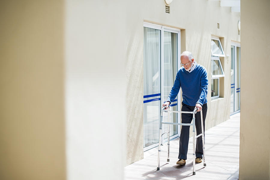 Senior man using walker on sidewalk Photograph by Portra