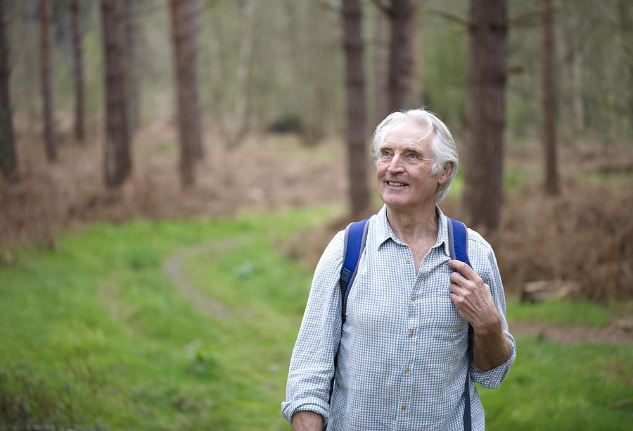 Senior man walking along forest path. Photograph by Dougal Waters