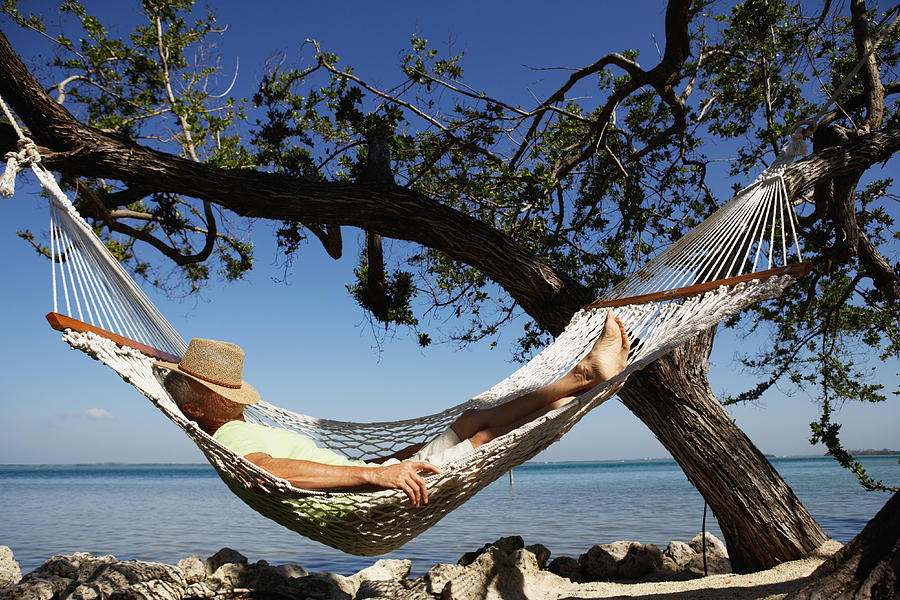 Senior man with hat on face sleeping in hammock, side view Photograph by Kraig Scarbinsky