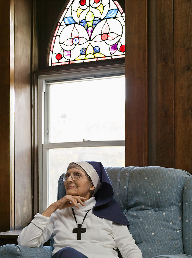 Senior nun sitting on arm chair, looking away Photograph by Martin San