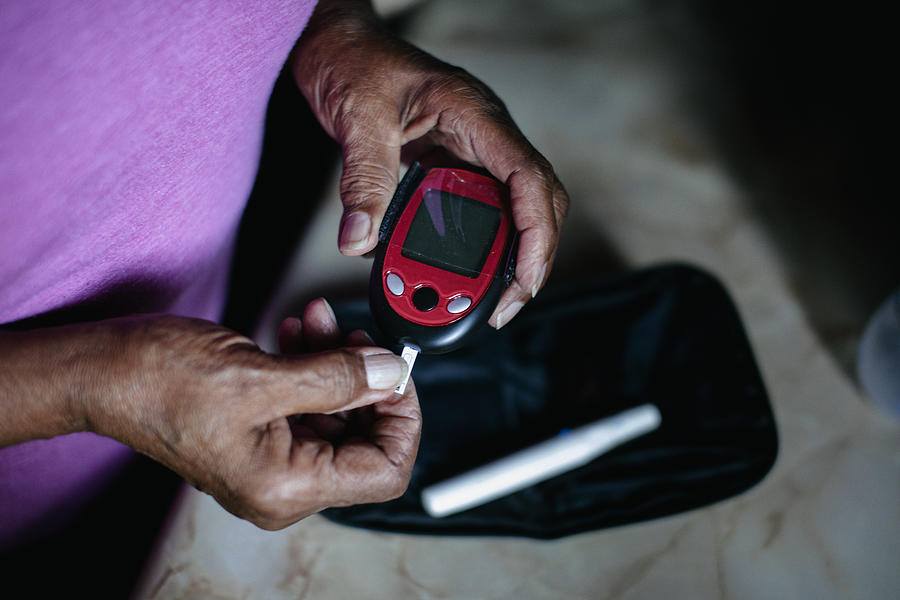Senior using diabetes home test kit Photograph by Willie B. Thomas