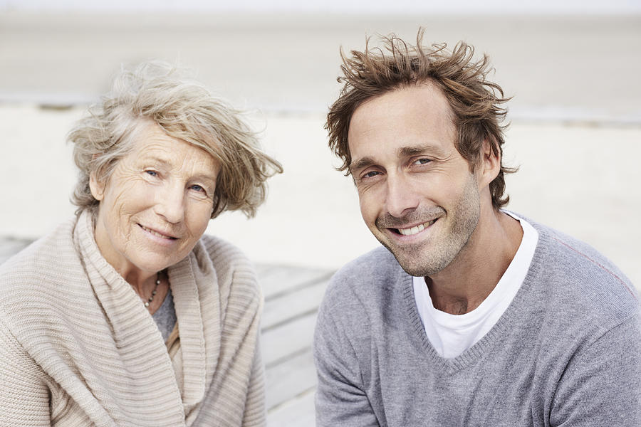 Senior woman and adult son on the beach, portrait Photograph by Oliver Rossi