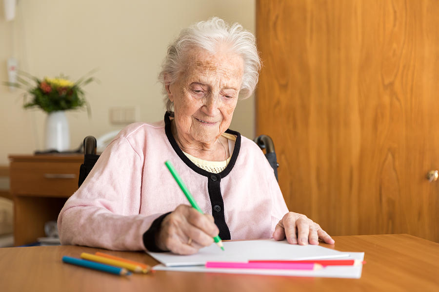 Senior woman drawing on white paper Photograph by FredFroese