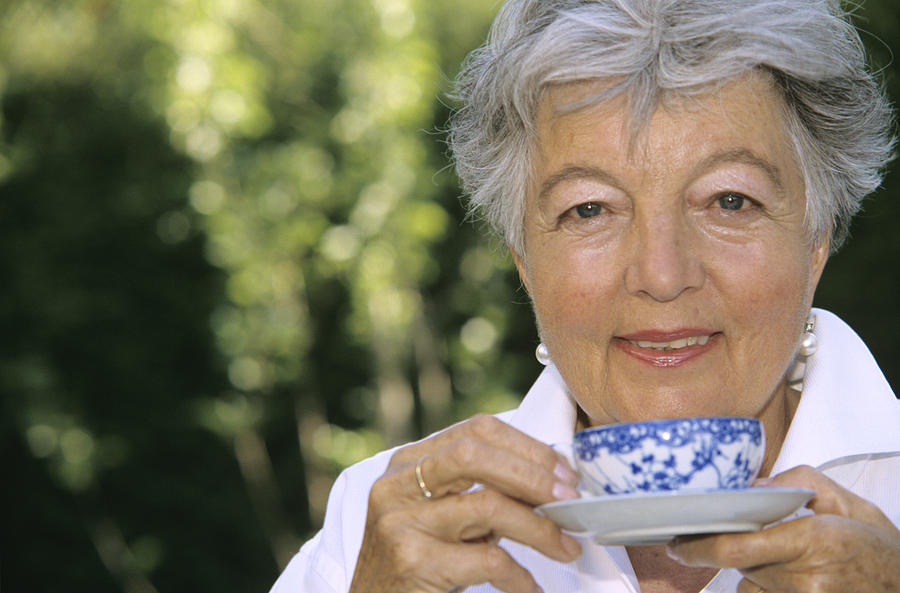 Senior woman holding cup of tea, close up Photograph by Petrol