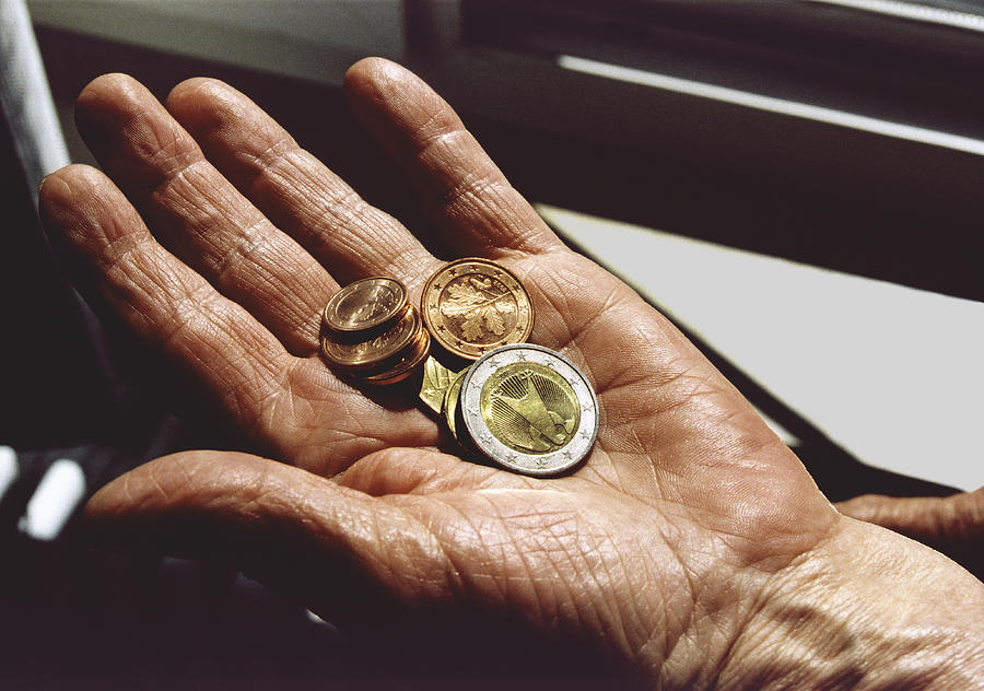 Senior woman holding Euro coins Photograph by Martin Diebel