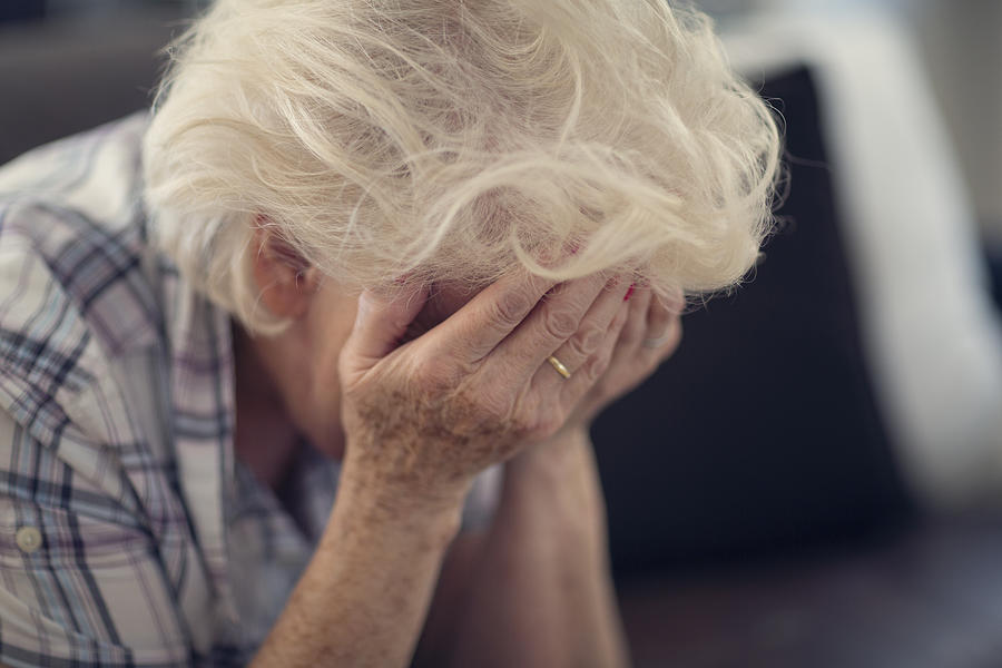 Senior woman holding head in hands in despair Photograph by Elva Etienne