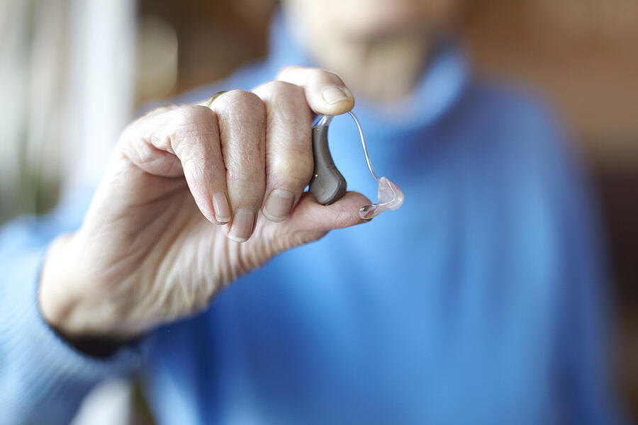 Senior woman holding hearing aid, close-up Photograph by Mara Ohlsson