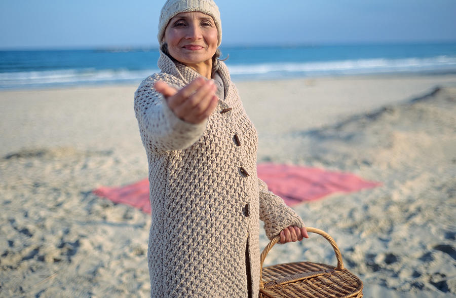 Senior woman holding picnic basket and beckoning Photograph by Image Source