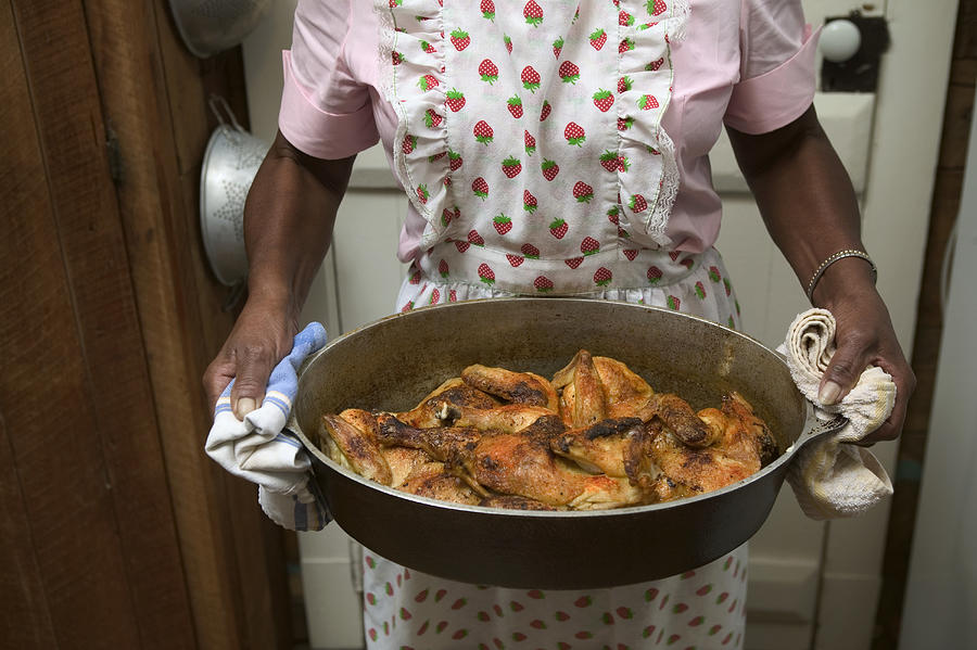 Senior woman holding pot with cooked chicken, mid section Photograph by Vegar Abelsnes Photography