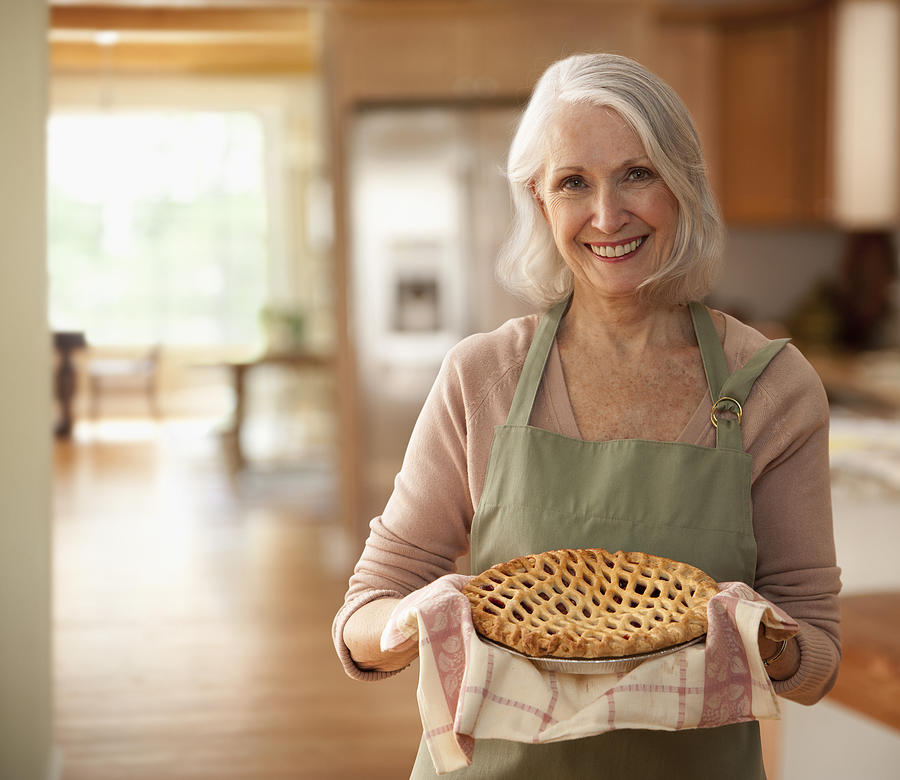 Senior woman holding up pie Photograph by SelectStock