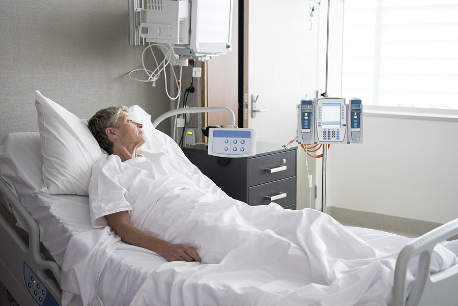 Senior woman lying in hospital bed looking away Photograph by JohnnyGreig