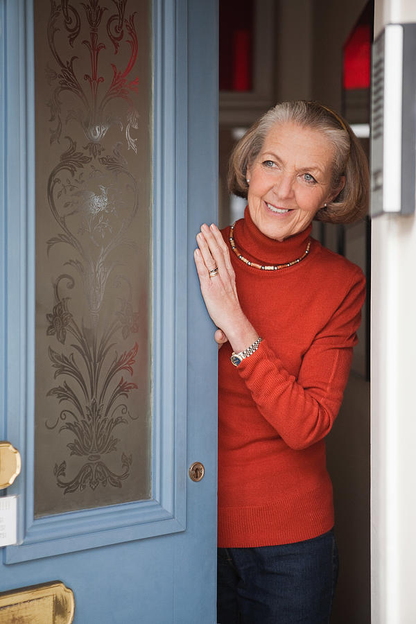 Senior woman opening front door Photograph by Image Source