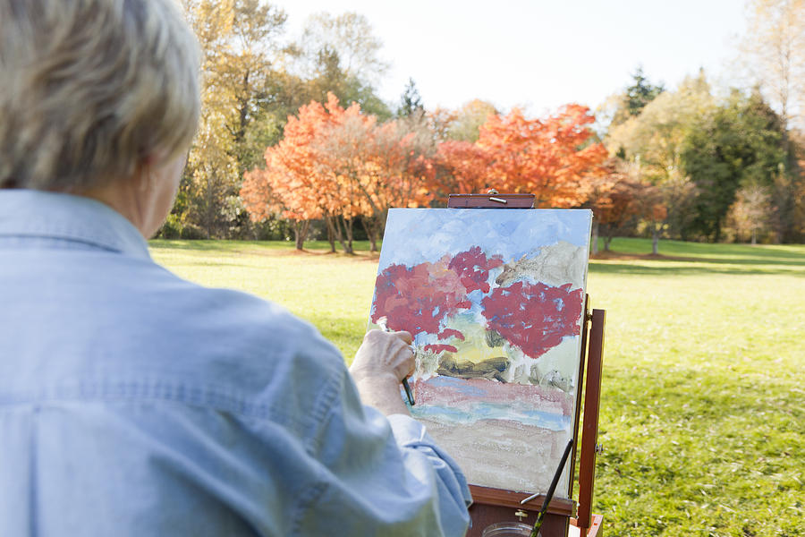 Senior woman painting outdoors Photograph by John Lee