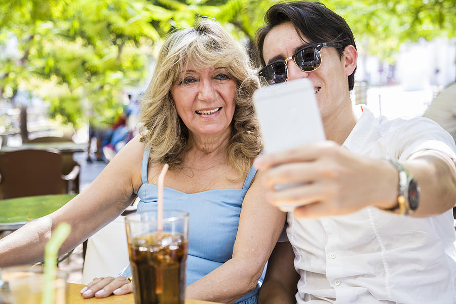 Senior woman taking a selfie with her grandson on restaurant Photograph by Richiesd
