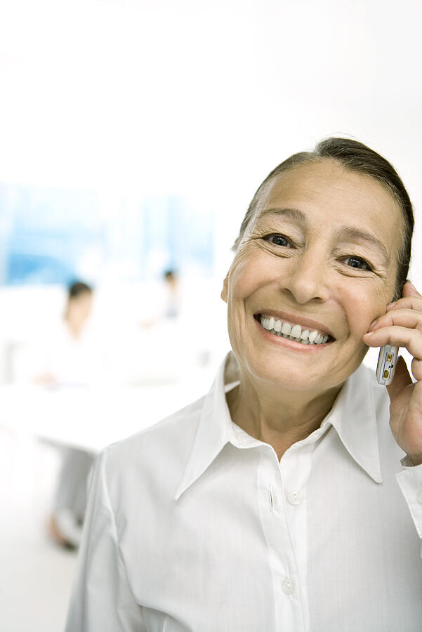 Senior woman using cell phone, smiling at camera Photograph by PhotoAlto/Sigrid Olsson