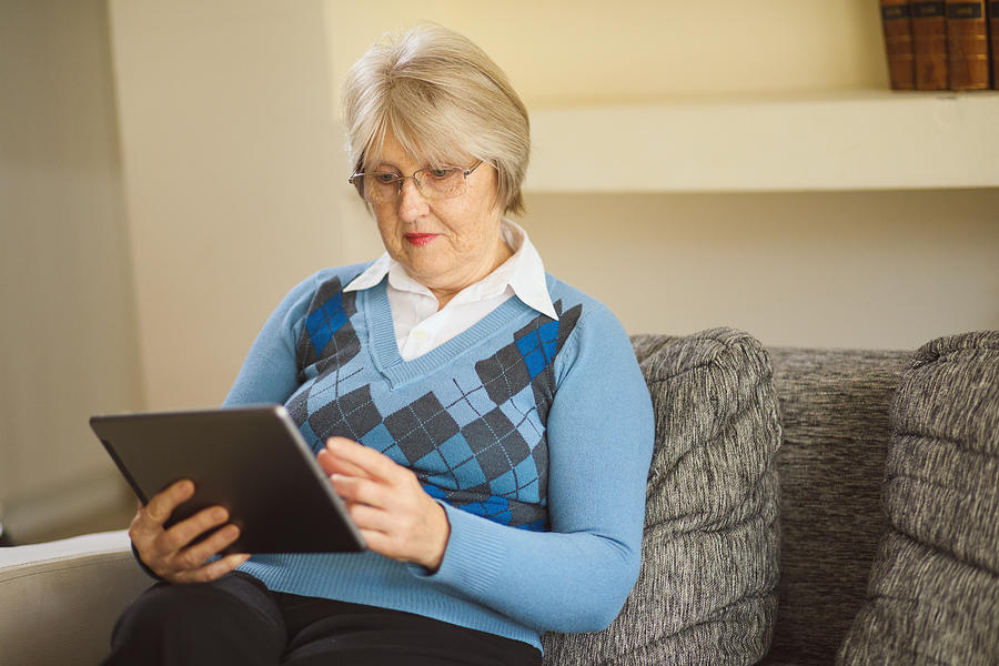 Senior woman using digital tablet at home Photograph by EmirMemedovski