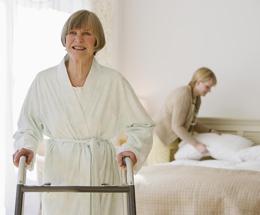 Senior woman using walker in bedroom Photograph by Tetra Images