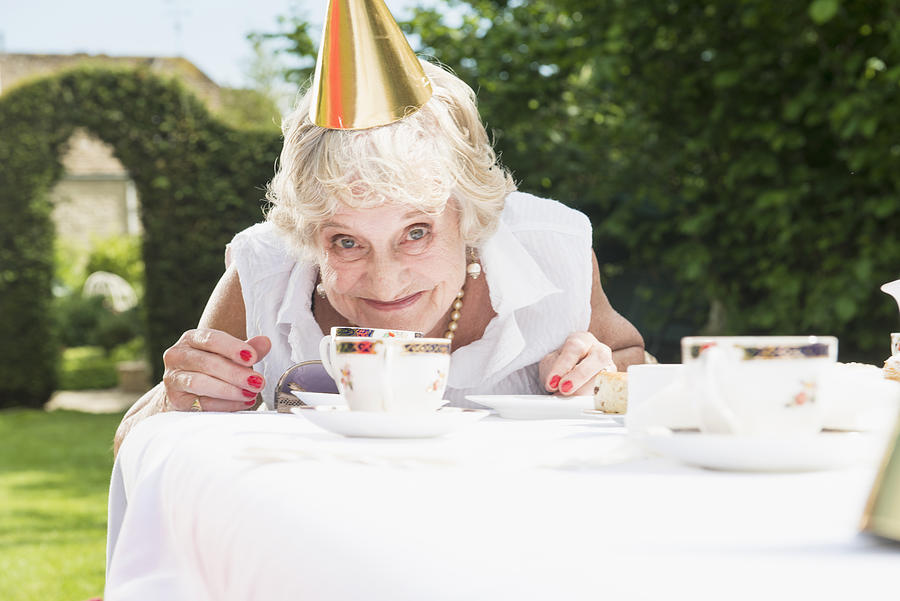 Senior woman wearing party hat looking at camera, smiling Photograph by Redheadpictures