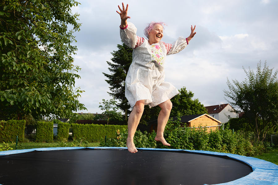 Senior woman with overweight jumping on trampoline Photograph by SilviaJansen