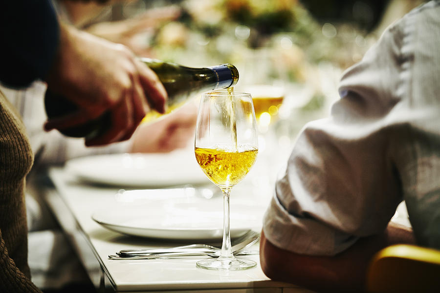 Server pouring glass of wine during dinner Photograph by Thomas Barwick