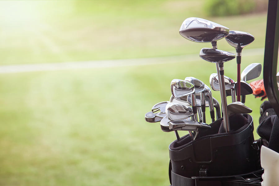 Set Of Golf Clubs Over Green Field Background Photograph