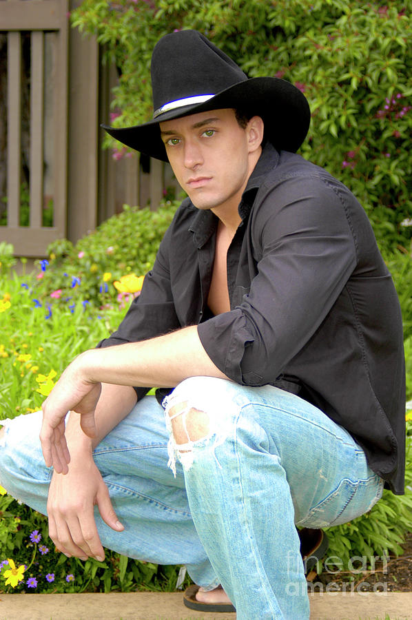 Sexy looking cowboy crouching down in a relaxed pose Photograph by Gunther Allen