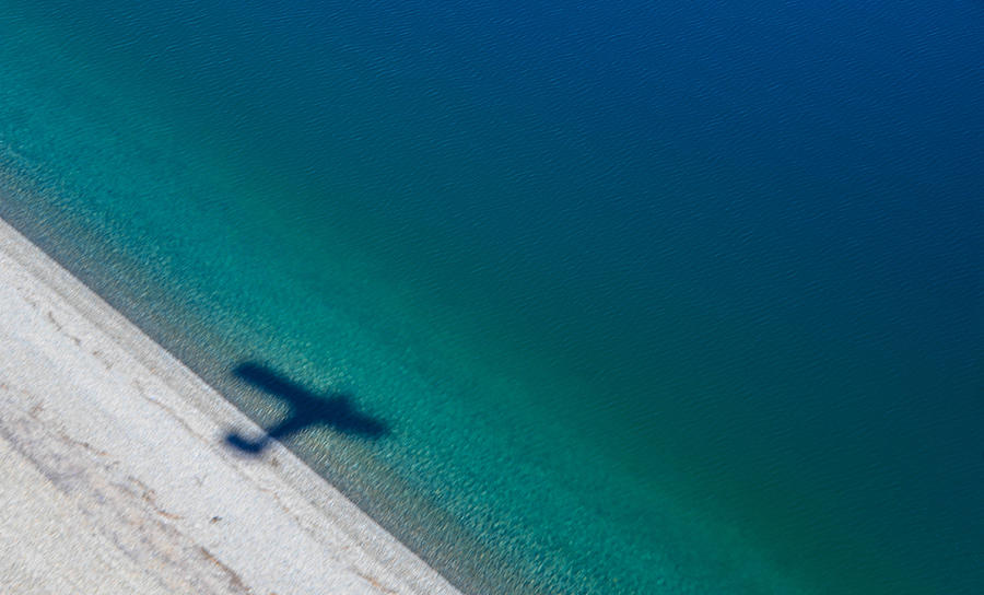 Shadow of a plane over lake coast Photograph by Marcos Radicella