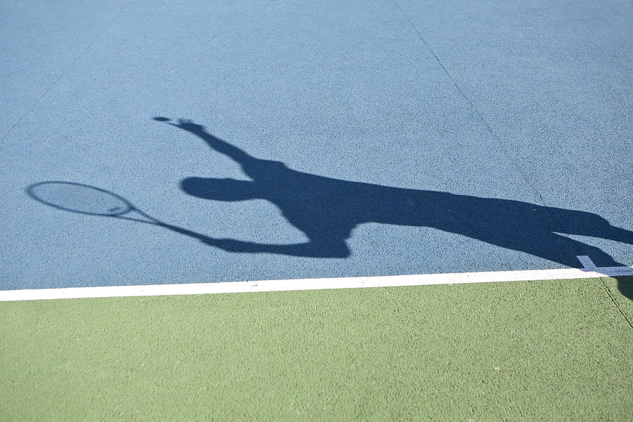 Shadow of tennis player serving ball Photograph by PhotoAlto/Laurence Mouton