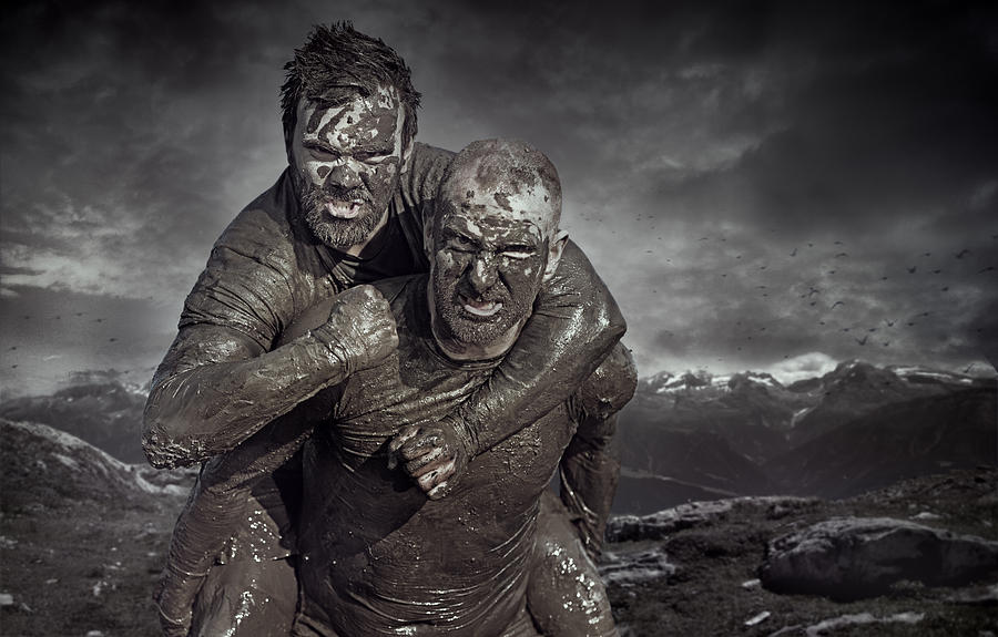 Shaved man carrying friend during a mud run Photograph by Lorado
