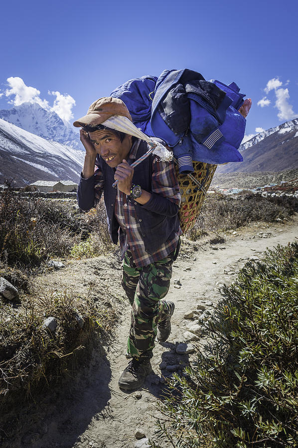 Sherpa porter carrying heavy basket along trail Himalayas Nepal Photograph by fotoVoyager