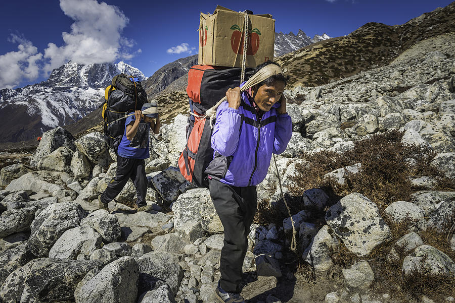 Sherpa porters carrying heavy loads on Himalaya mountain trail Nepal Photograph by fotoVoyager