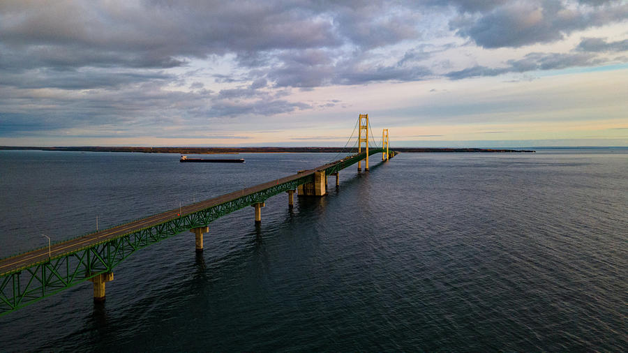 Ship passing by the Mackinac Bridge at sunrise Photograph by Eldon McGraw